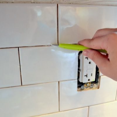 clean tile adhesive from grout lines with a small utility knife