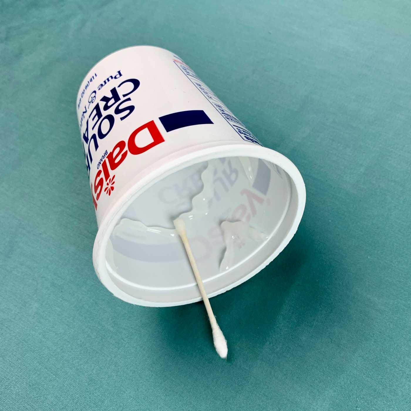 container with q tip on glue